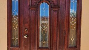 Una puerta doble de madera con paneles de vidrio y detalles metálicos decorativos.