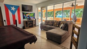 Una sala de estar con mesa de billar, sofá y televisor.