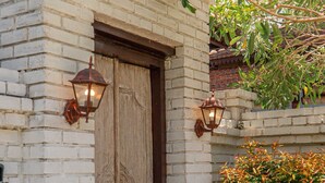 A white brick building with a wooden door and two lantern-style lights. - Sakya Villa (Canggu)