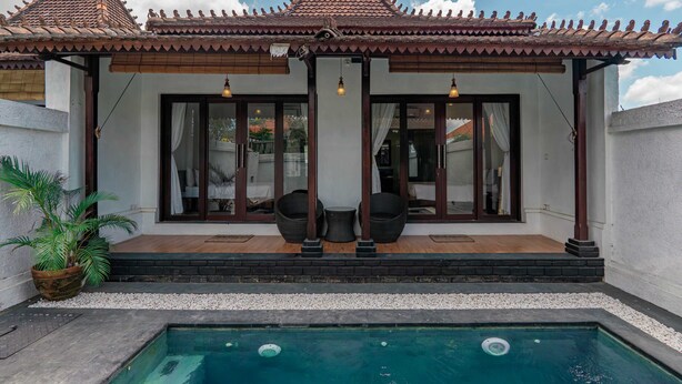 A traditional house with a tiled roof, a swimming pool, and two wicker chairs under a covered porch. - Sakya Villa (Canggu)