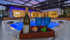Ein Whirlpool mit einer Weinflasche, zwei blauen Gläsern, einem Korb mit Snacks und einem Korbtablett.