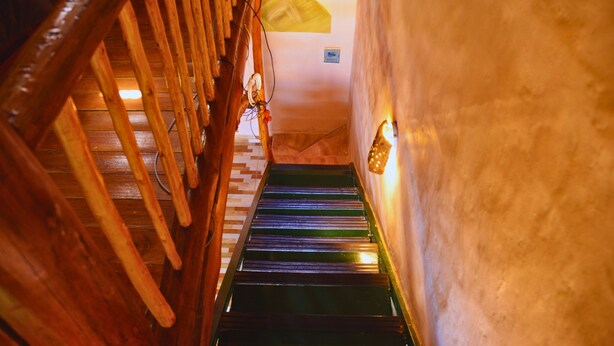 Un escalier en bois, doté d’une rampe et d’un luminaire fixé au mur.