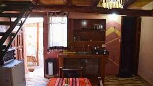 Une cuisine de taille réduite, dotée d’un comptoir en bois, d’un réfrigérateur et d’un coin repas avec une table et des chaises.
