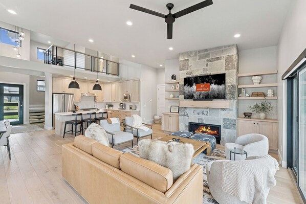 Una sala de estar moderna con chimenea, televisor y ventilador de techo alto.