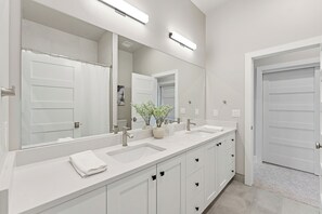 Un baño moderno con lavamanos doble, un espejo grande y una planta en maceta.