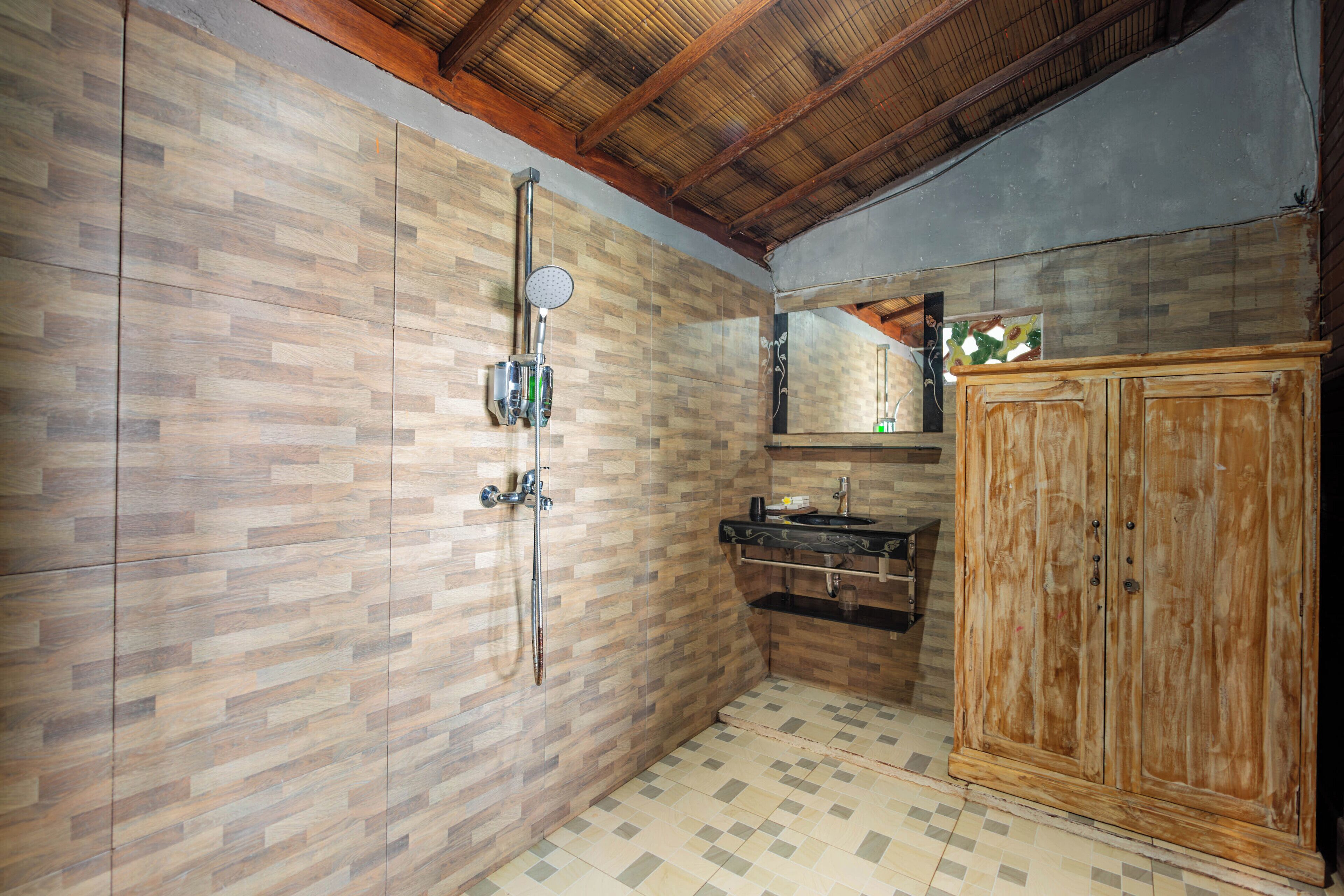 A bathroom with wooden walls, a shower, a sink, and a cabinet.