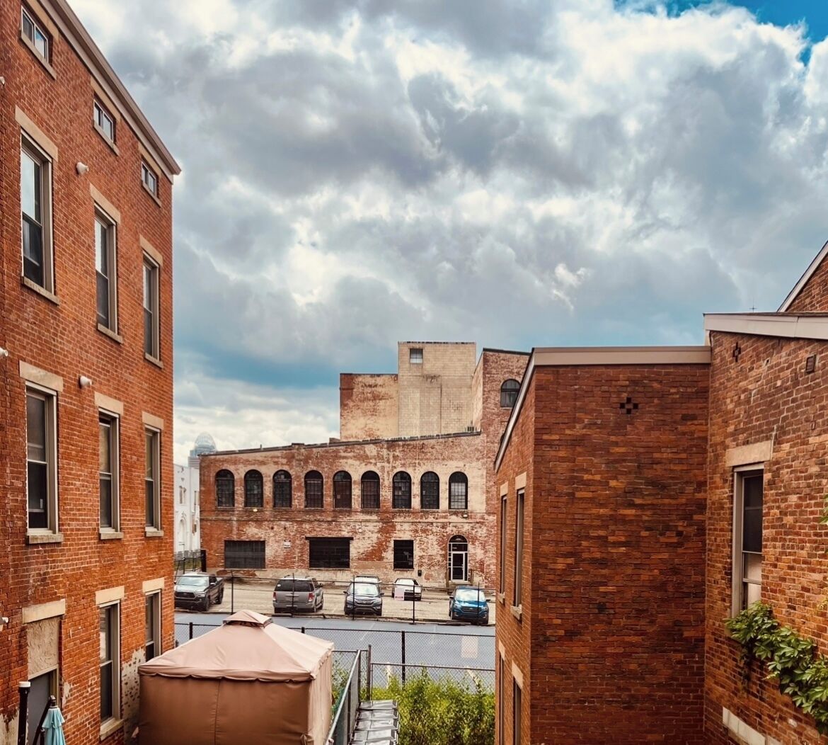 A courtyard with brick buildings, a parking area, and a clear sky.