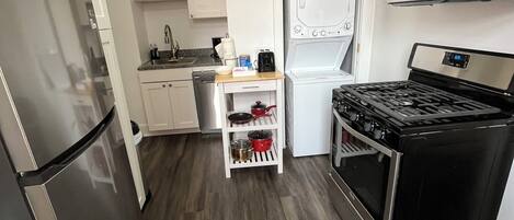 A compact kitchen with a stainless steel refrigerator, a microwave, a stove, and a dishwasher.
