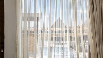 Ein Zimmer mit Blick auf eine Pyramide, durch transparente Vorhänge.