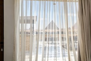Una habitación con vistas a una pirámide, separada por cortinas de gasa.