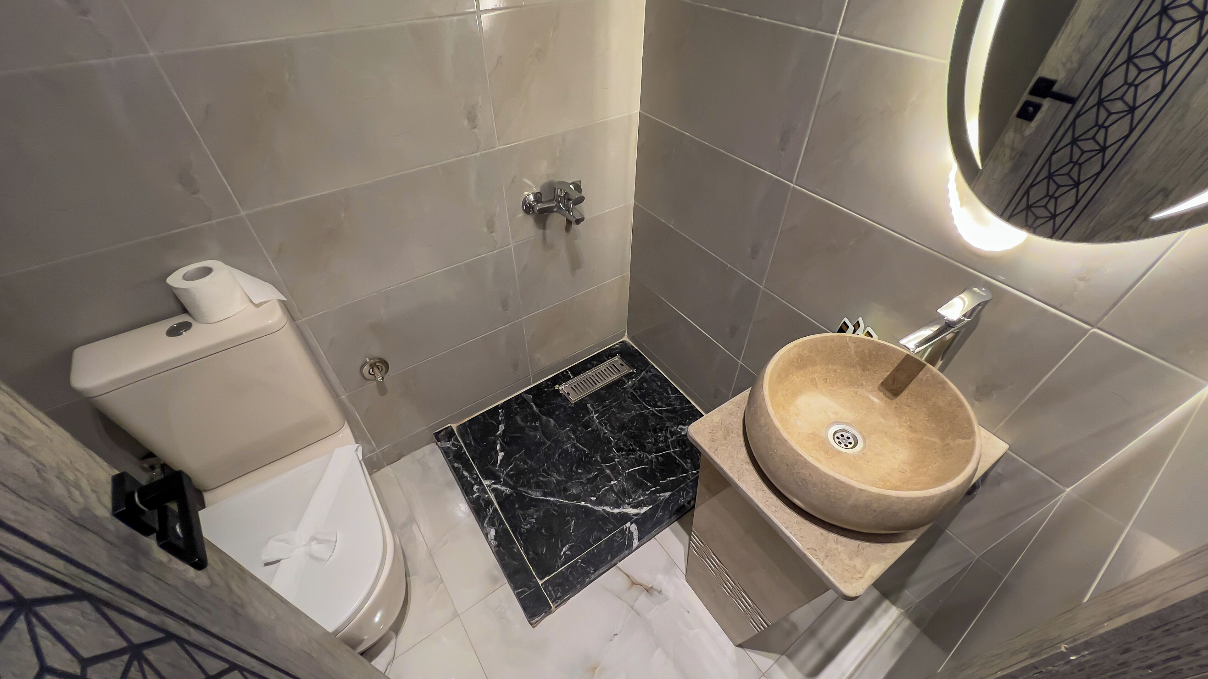 Baño con inodoro, lavamanos con encimera de mármol y zona de ducha.