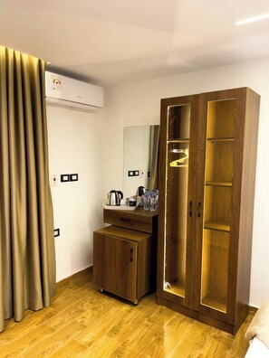 A hotel room with a wardrobe, a small desk with a kettle, a mirror, and a water dispenser. - Point Pyramids View Inn (Giza)