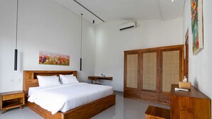 A modern bedroom with a wooden bed, bedside tables, a desk, and a wardrobe. - Theodosia Villa (Kutuh)