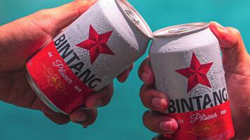 Two hands holding a can of Bintang beer.