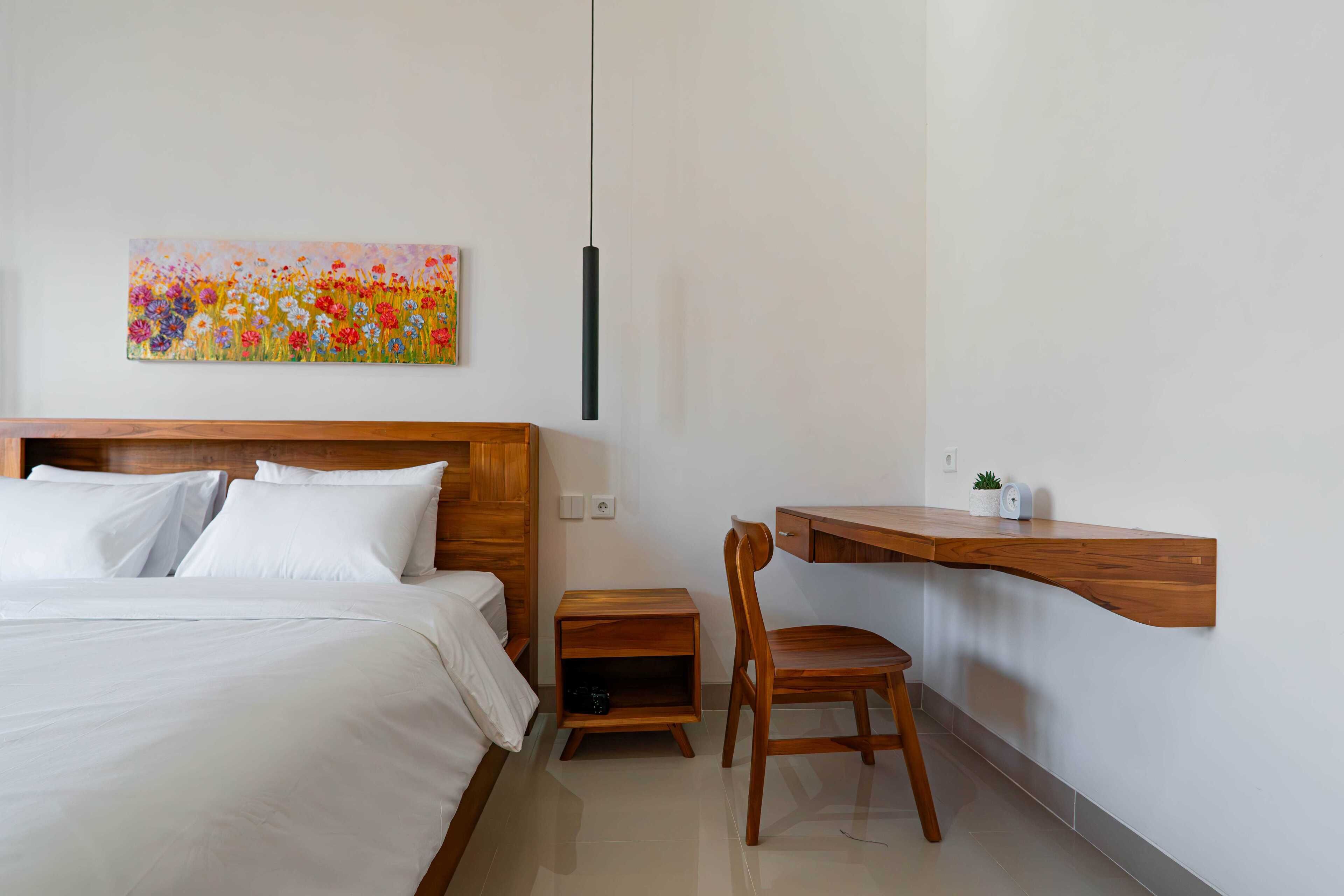 Une chambre à coucher comprenant un lit, une table de chevet en bois, une chaise, un bureau et une étagère fixée au mur.