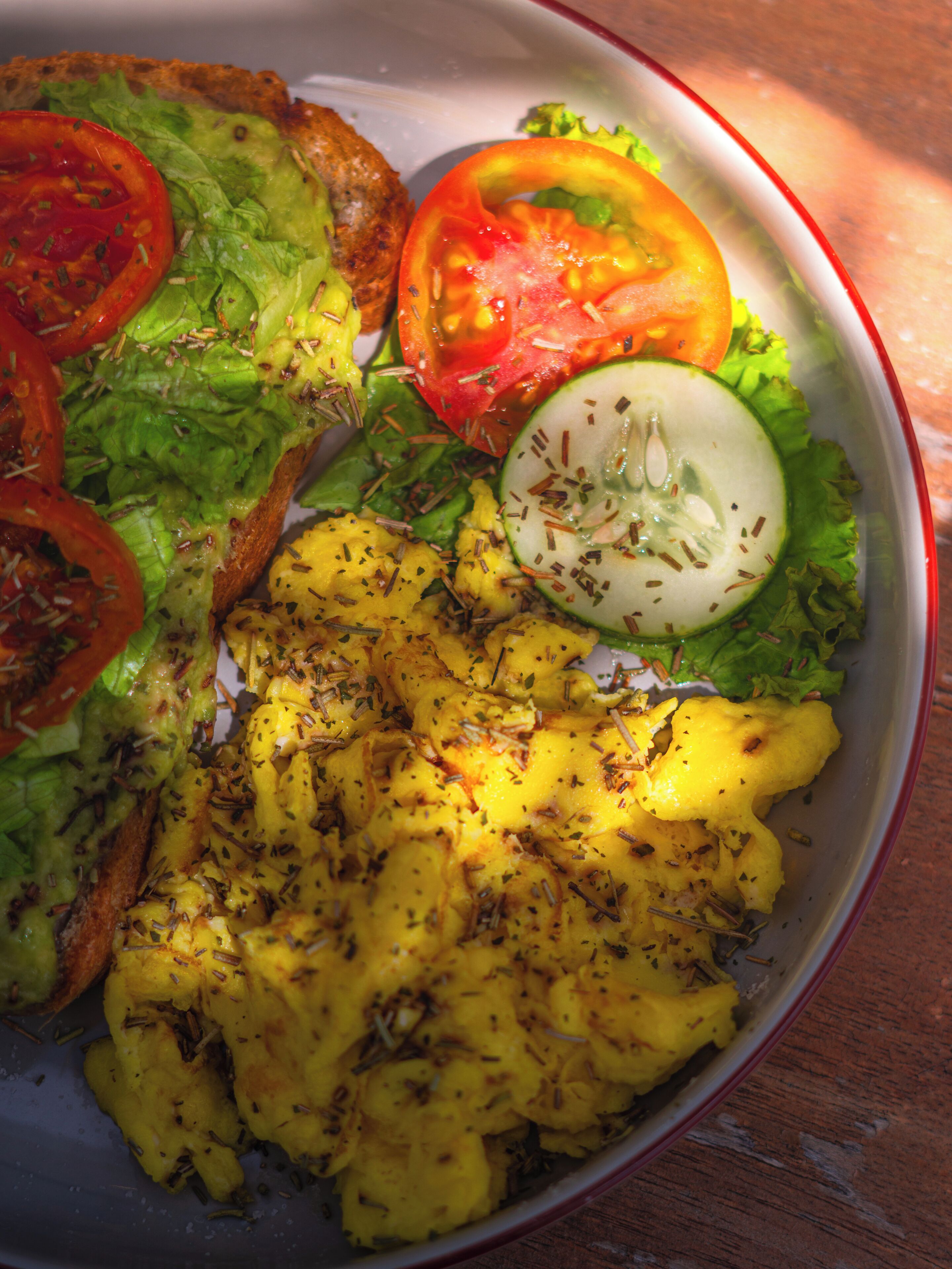 Un plato de comida con verduras variadas y una rebanada de pan.