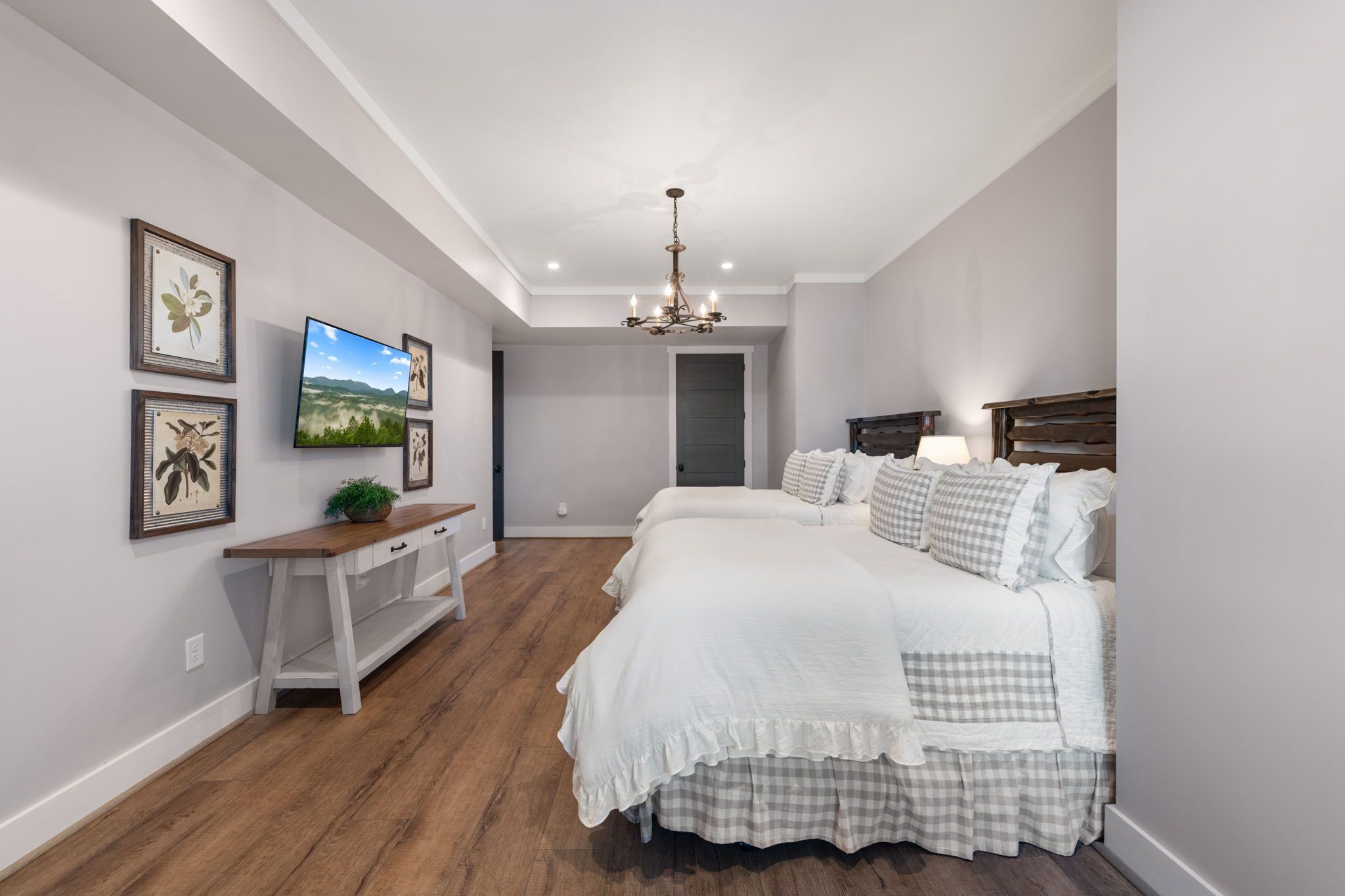 Quarto com cama grande, televisão e escrivaninha com planta.