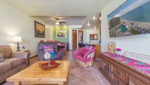 A living room with a wooden coffee table, two sofas, a dining area, and a kitchen.
