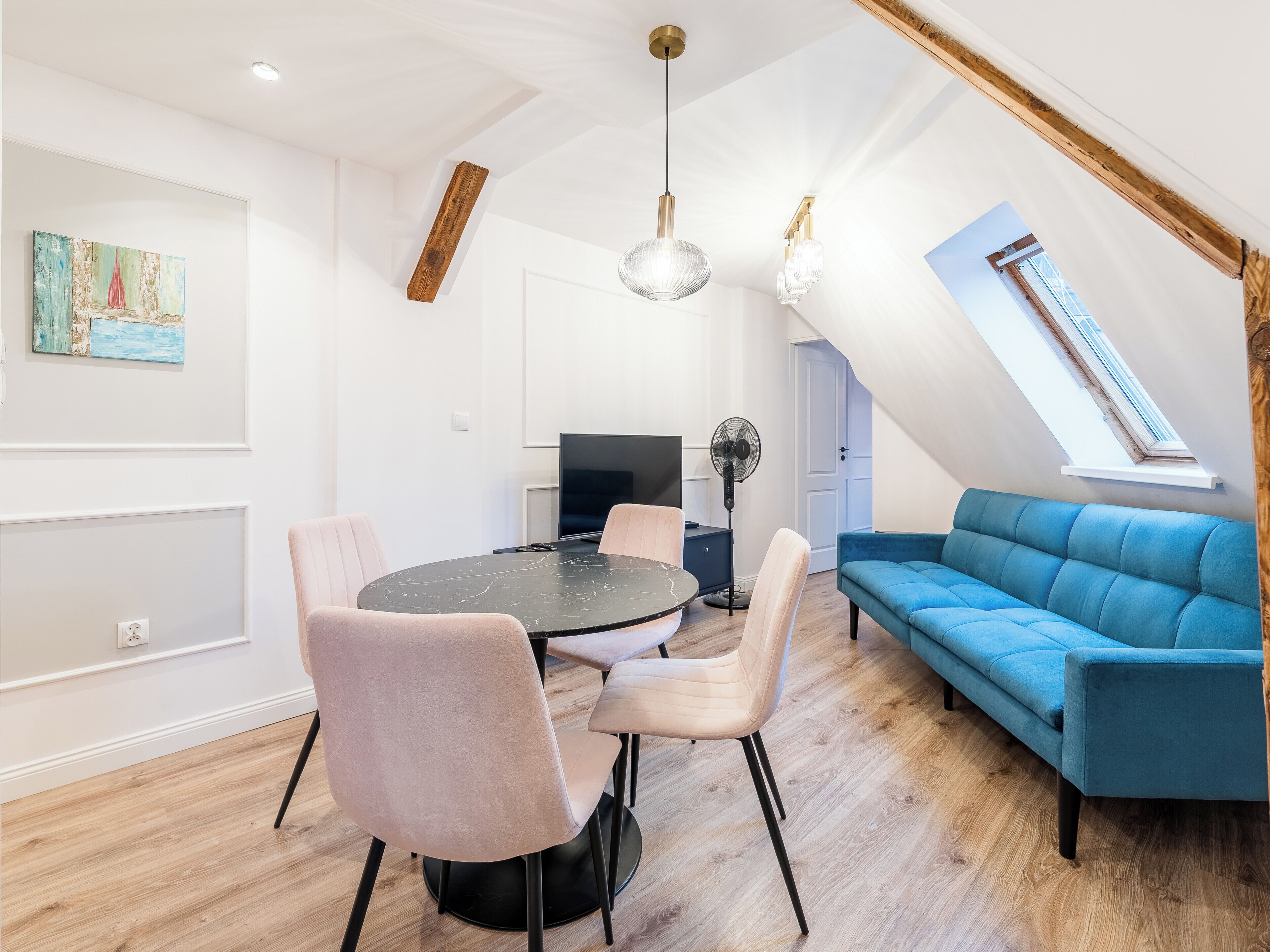Un loft moderno con comedor, sala de estar con sofá azul y tragaluz.