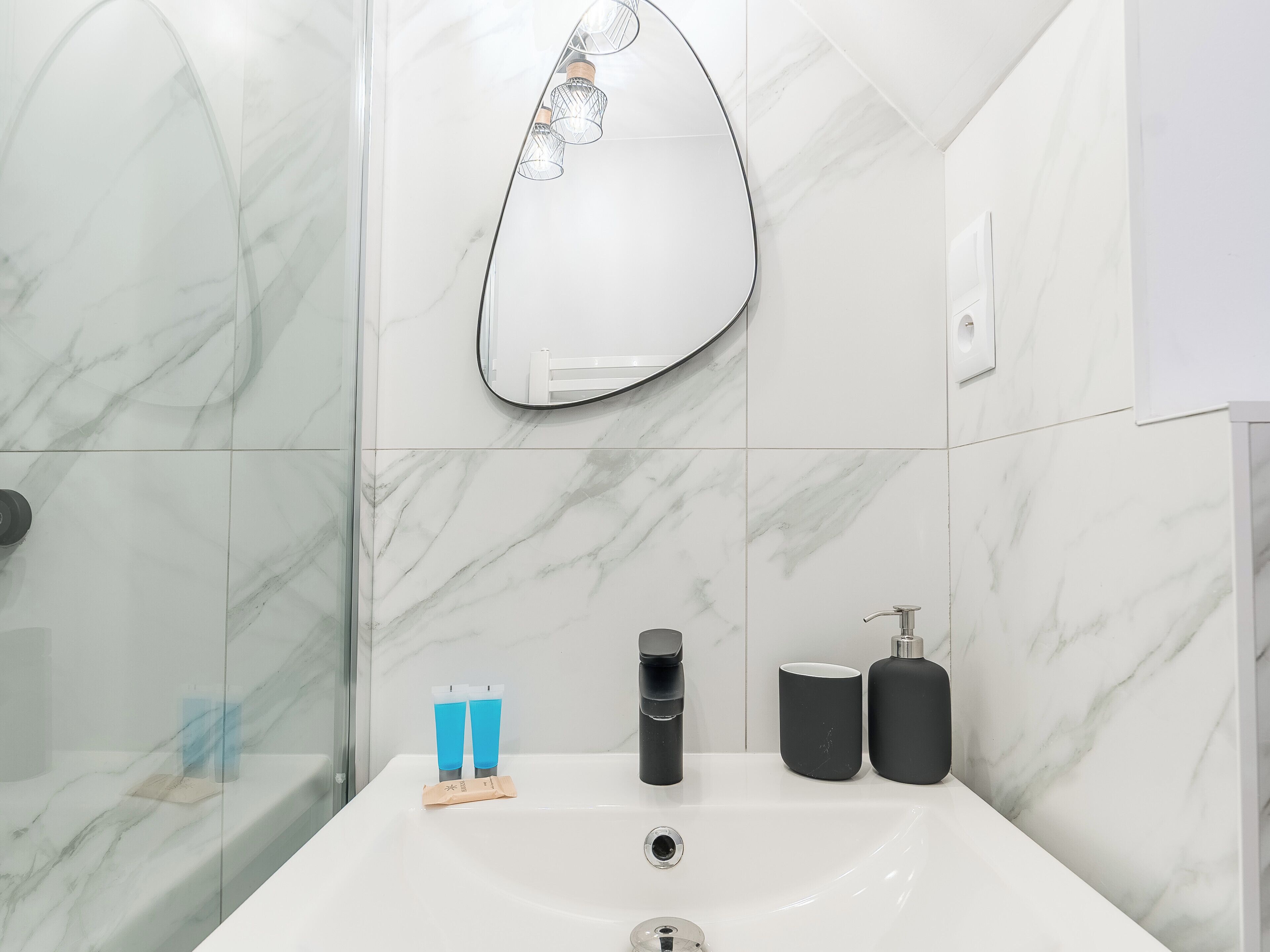 A bathroom with a white sink, a mirror, and toiletries.