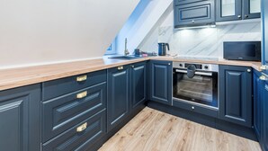 A modern kitchen with dark blue cabinets, a wooden countertop, and a built-in oven.
