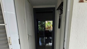 Un couloir menant à une porte sur laquelle est posé un paillasson avec l’inscription « BIENVENUE ».