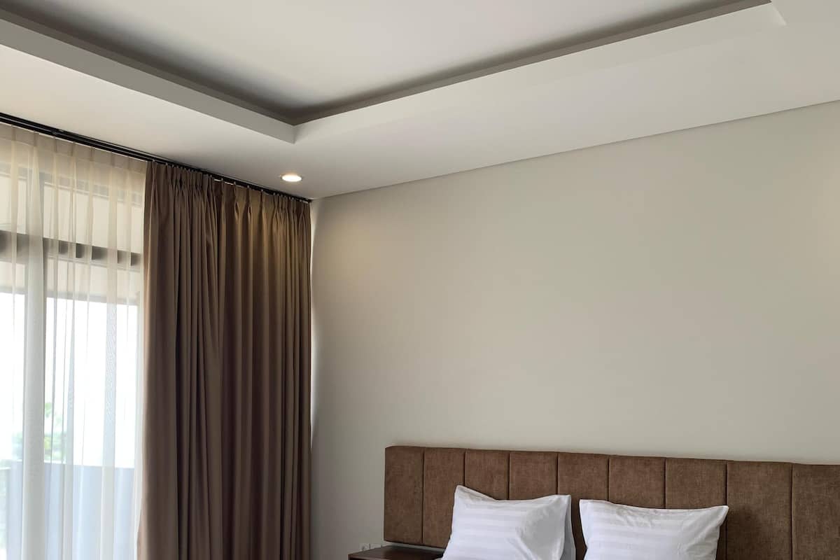 Une chambre d’hôtel moderne avec un grand lit, une tête de lit en bois et une table de chevet.