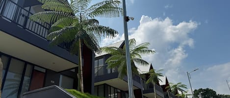 A modern building with balconies, a stone retaining wall, and a clear sky.