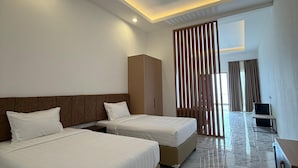 A modern hotel room with two beds, a wardrobe, a desk with a chair, and a large window with curtains. - Wind Hill Mountain View Resort (Megamendung)