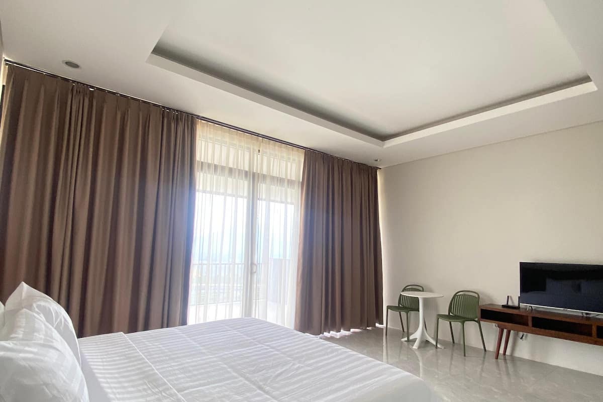 Une chambre d’hôtel avec un grand lit, une télévision, une petite table et des chaises.