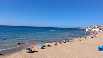 Une plage avec des gens, des parasols et des bateaux.