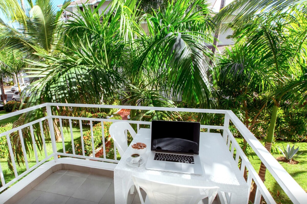 Un balcone con un portatile, una tazza di caffè e una ciotola di noci.