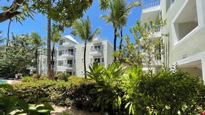 Een resort met meerlaags gebouwen, een zwembadgedeelte en weelderige begroeiing.