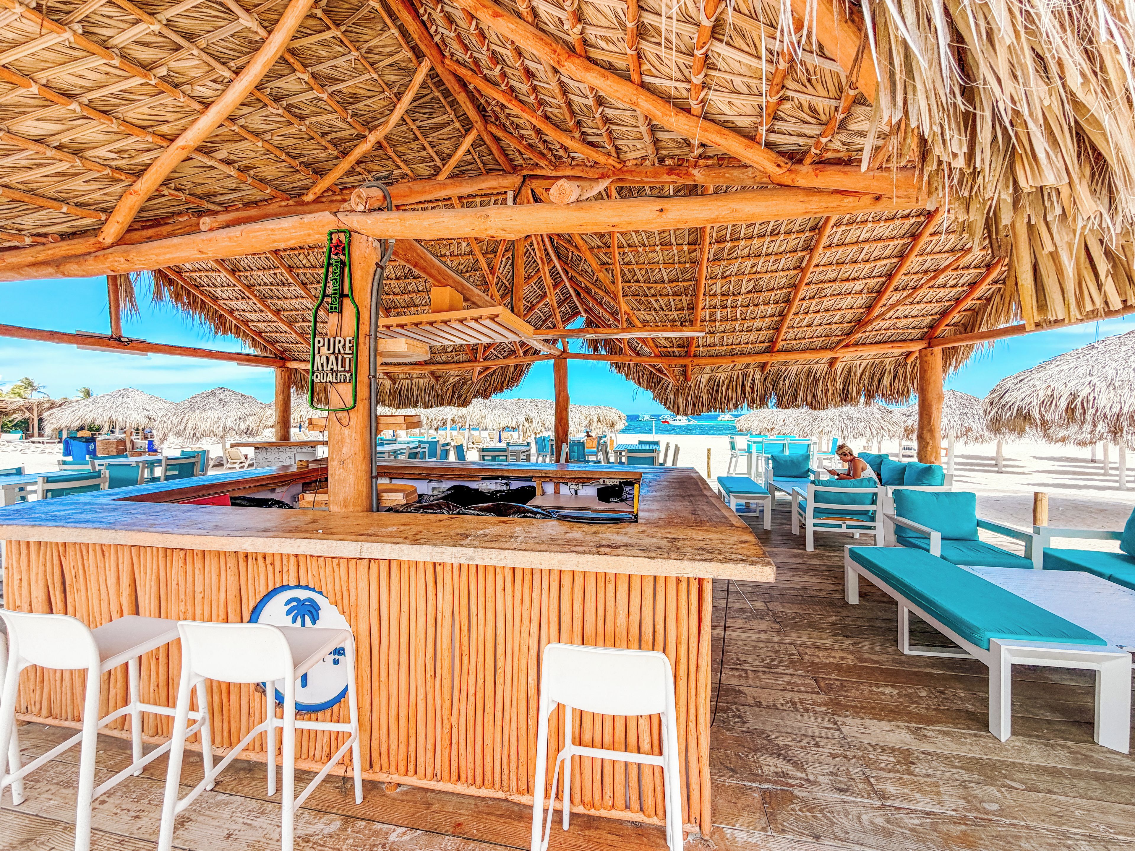 Eine Strandbar mit Holzmöbeln und einem Reetdach.