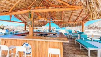 Eine Strandbar mit Holzmöbeln und einem Reetdach.
