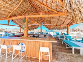 Un bar en la playa con muebles de madera y techo de paja.