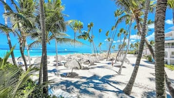 Perto da praia, areia branca, espreguiçadeiras, guarda-sóis