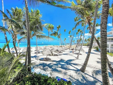 Una playa cerca, arena blanca, sillas reclinables de playa, sombrillas