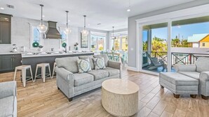 A modern kitchen with a central island, a grey sofa, and a round coffee table. - Amazing home on canal! Paddle boards, and kayaks! (Bradenton Beach)