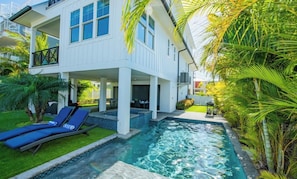 Ett modernt hus med en swimmingpool, en täckt uteplats och en balkong.