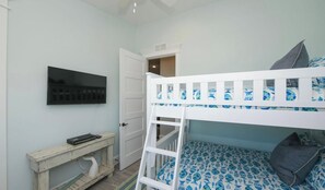 Un lit superposé avec une échelle, un bureau avec une chaise et un téléviseur fixé au mur.