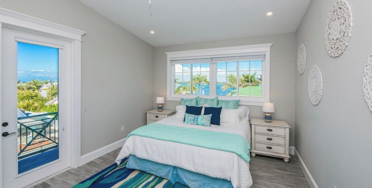 A bedroom with a bed, bedside tables, a window with a view, and decorative wall art.