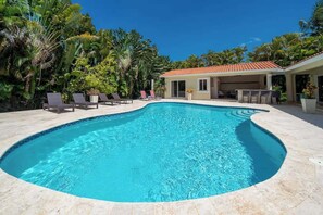 A swimming pool with lounge chairs and a covered patio area.