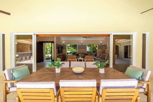 An open-plan living area with a dining table, sofas, and a view into the kitchen.