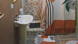 Un bagno con lavandino, specchio, doccia e tenda da doccia fantasia.