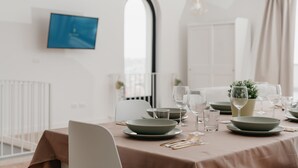 Un coin repas avec une table dressée pour quatre personnes, comprenant des assiettes, des bols, des verres et des couverts.