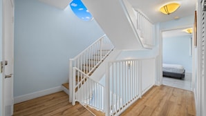 A staircase with white railings leading to a bedroom with a bed and a ceiling light fixture.