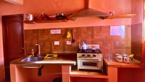 Uma cozinha compacta com fogão a gás, forno e bancada de madeira.