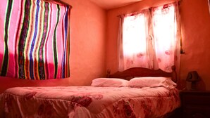 Quarto com uma cama de solteiro, cabeceira de madeira e mesa de cabeceira com abajur.