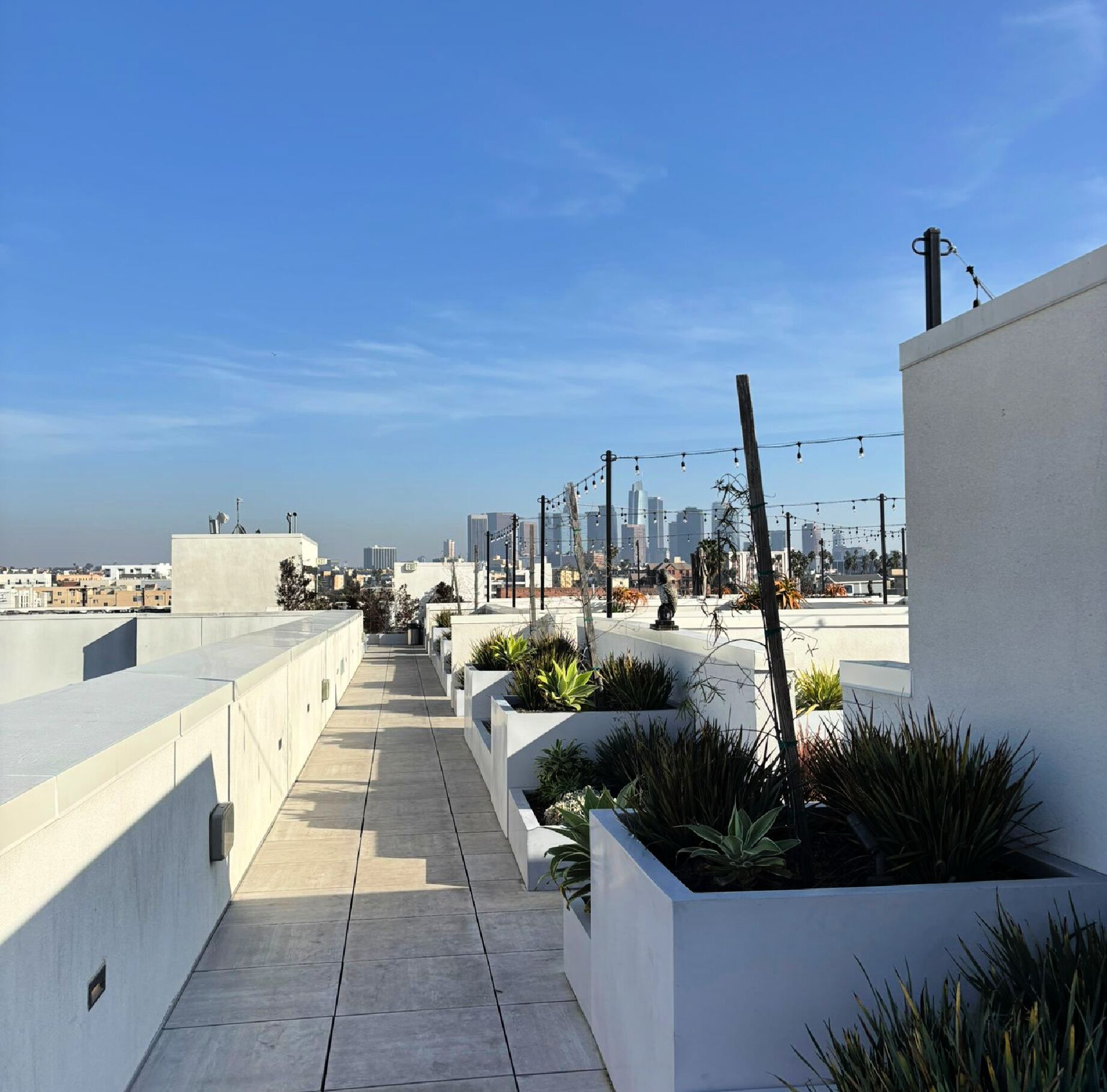 Une terrasse sur le toit offrant une vue dégagée sur les gratte-ciel de la ville, avec des bâtiments modernes et une promenade dallée.